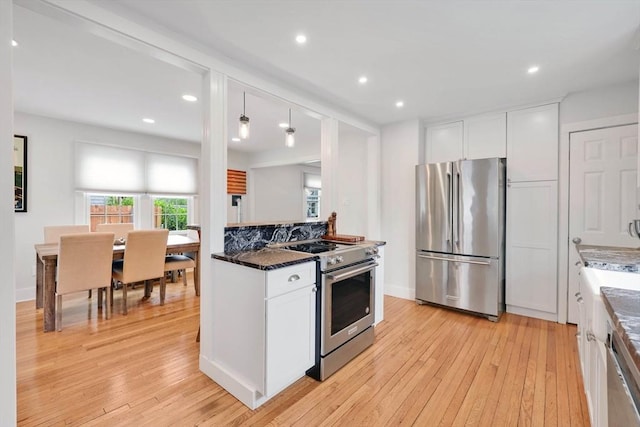 kitchen featuring stainless steel appliances, light wood-style floors, white cabinetry, recessed lighting, and dark stone countertops