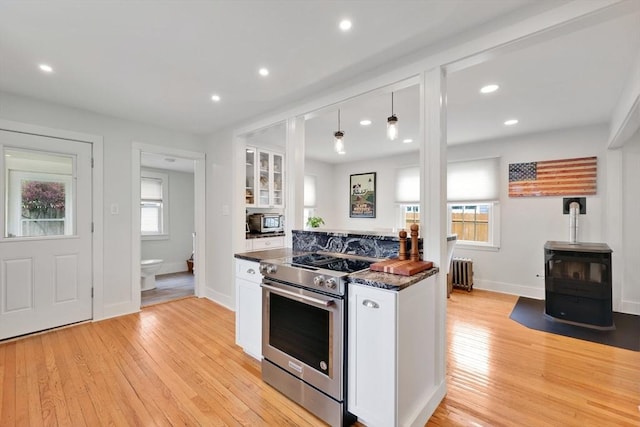 kitchen with stainless steel range with electric cooktop, radiator, white cabinetry, light wood finished floors, and recessed lighting