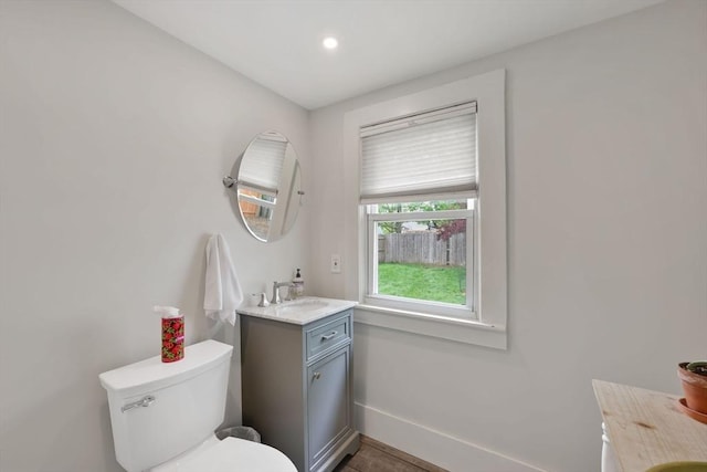 bathroom featuring baseboards, vanity, toilet, and recessed lighting
