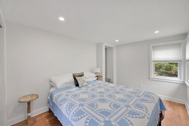 bedroom featuring baseboards, wood finished floors, and recessed lighting