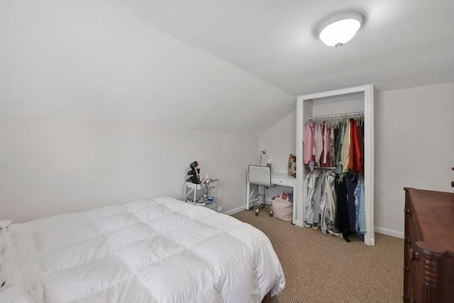 carpeted bedroom with lofted ceiling, a closet, and baseboards