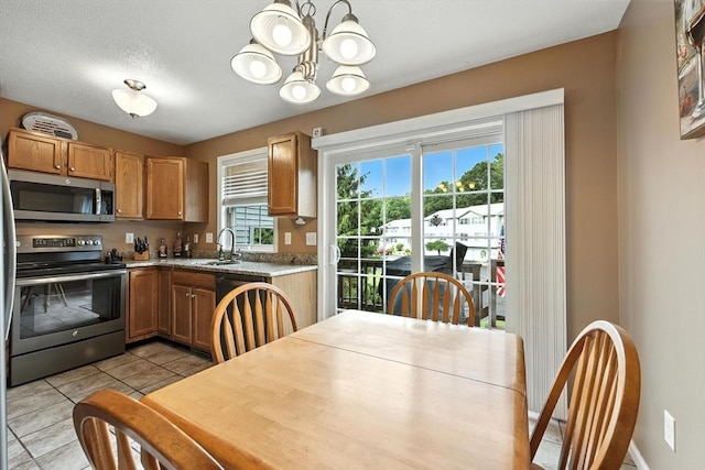 50 Waters Edge Unit 50, Ludlow, MA 01056 - kitchen featuring appliances with stainless steel finishes, a chandelier, light countertops, light tile patterned flooring, and brown cabinets