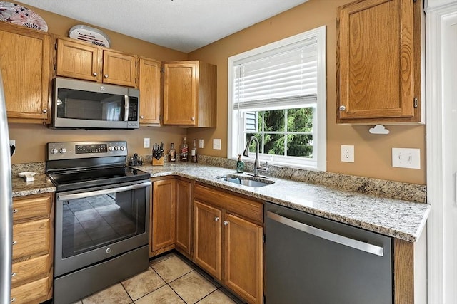 50 Waters Edge Unit 50, Ludlow, MA 01056 - kitchen featuring stainless steel appliances, light tile patterned flooring, light stone countertops, and brown cabinetry