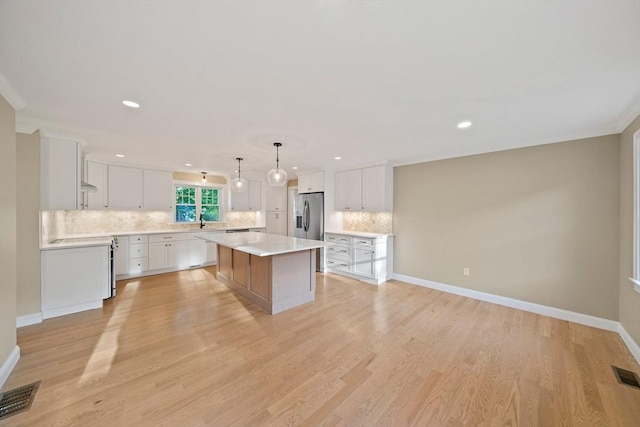 56 Lake St, Braintree, MA 02184 - kitchen featuring stainless steel refrigerator with ice dispenser, a kitchen island, backsplash, light countertops, and white cabinets