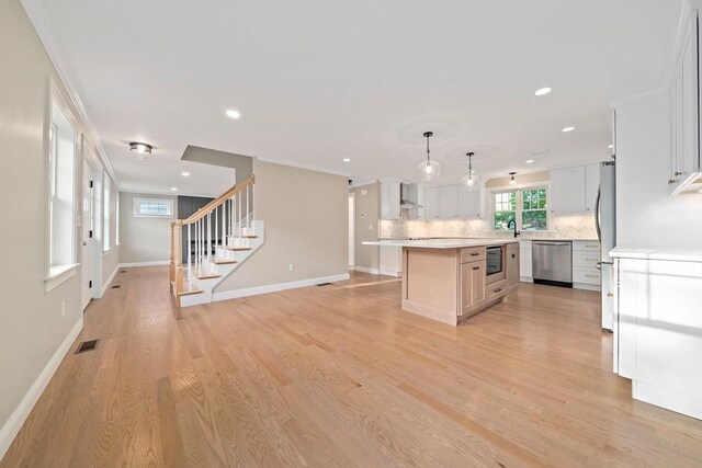 56 Lake St, Braintree, MA 02184 - kitchen featuring stainless steel appliances, tasteful backsplash, light countertops, a center island, and light wood-style flooring