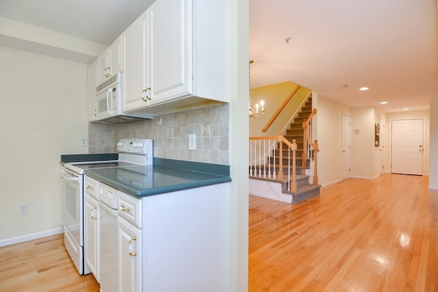 kitchen featuring white appliances, light wood-type flooring, backsplash, white cabinets, and an inviting chandelier