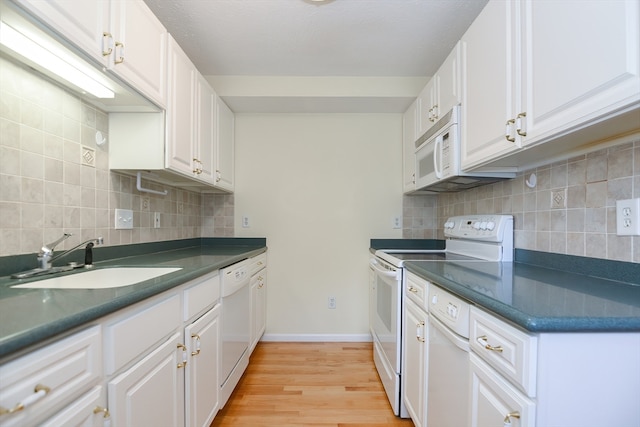 kitchen with white appliances, light hardwood / wood-style flooring, sink, and white cabinets