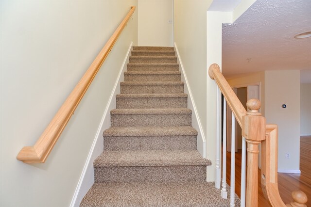 stairs featuring wood-type flooring and a textured ceiling