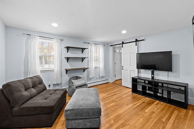 living room featuring a baseboard radiator, a barn door, and wood-type flooring