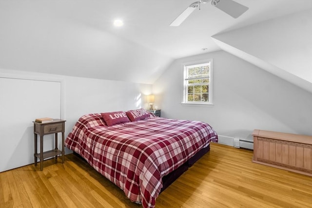 bedroom with vaulted ceiling, ceiling fan, hardwood / wood-style floors, and a baseboard heating unit