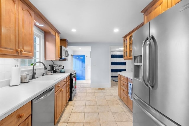 kitchen with light tile patterned floors, stainless steel appliances, sink, and backsplash