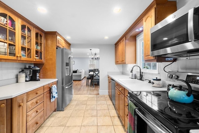 kitchen with sink, tasteful backsplash, a chandelier, light tile patterned floors, and stainless steel appliances