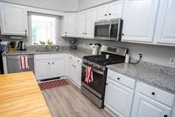 185 Baldwinville Rd, Winchendon, MA 01475 - kitchen with appliances with stainless steel finishes, white cabinets, light wood finished floors, and a sink