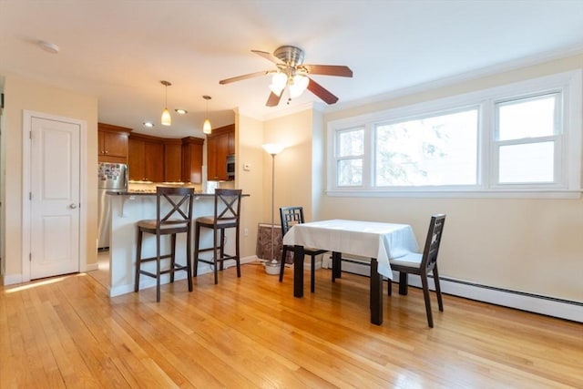 dining room with crown molding, ceiling fan, baseboards, light wood-style flooring, and a baseboard radiator