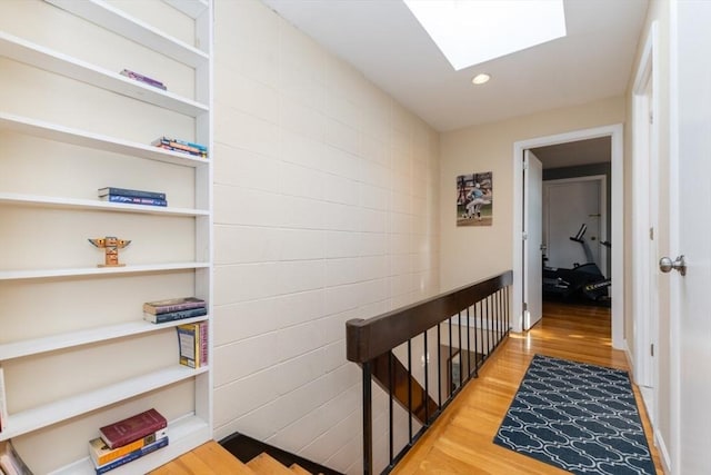 corridor with recessed lighting, a skylight, and wood finished floors