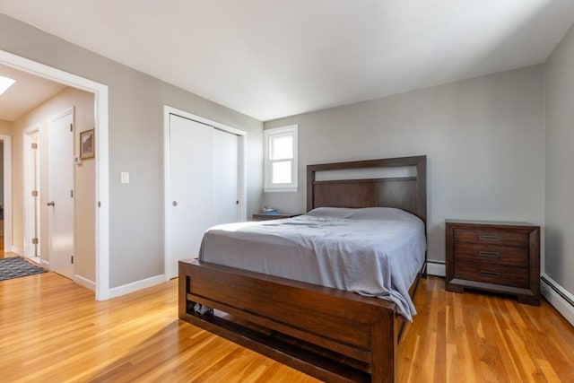 bedroom with a closet, baseboard heating, light wood-type flooring, and a baseboard radiator