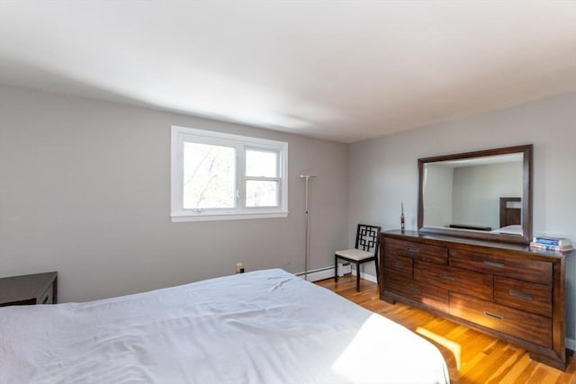 bedroom featuring a baseboard heating unit and light wood-type flooring