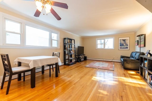 dining room with light wood-style floors, baseboard heating, and crown molding