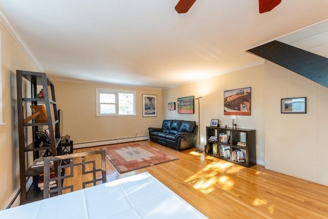 living area featuring baseboard heating, ornamental molding, ceiling fan, and wood finished floors