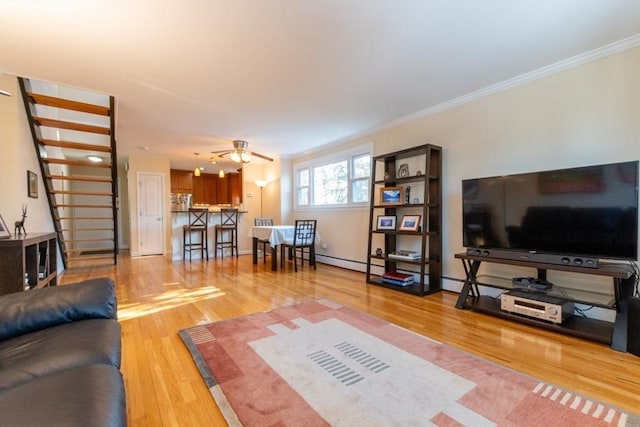 living area featuring stairway, wood finished floors, a ceiling fan, and ornamental molding