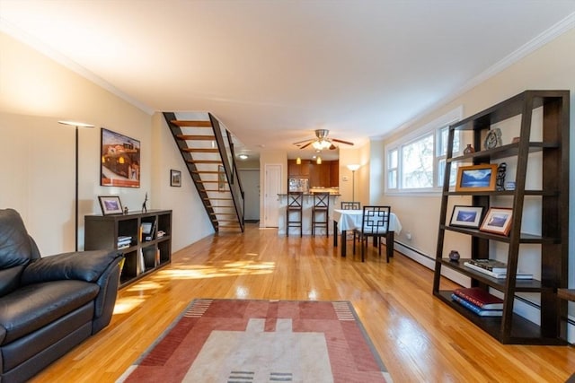 living area featuring stairway, light wood-style floors, crown molding, and a ceiling fan