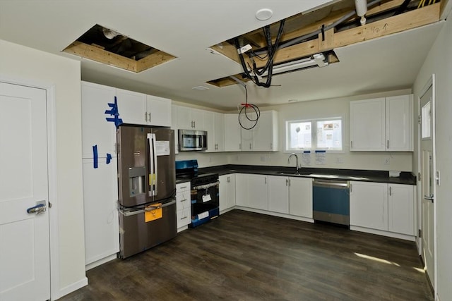 205 Clemente St, Holyoke, MA 01040 - kitchen with appliances with stainless steel finishes, dark countertops, dark wood-style flooring, and white cabinetry
