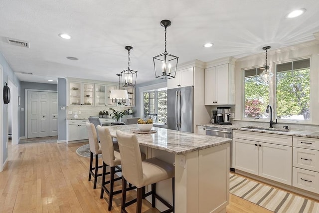 9 Bateson Dr, Andover, MA 01810 - kitchen featuring stainless steel appliances, a sink, decorative backsplash, a kitchen island, and glass insert cabinets