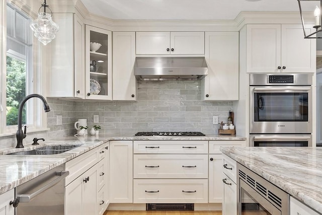 9 Bateson Dr, Andover, MA 01810 - kitchen with stainless steel appliances, exhaust hood, a sink, light stone counters, and white cabinetry