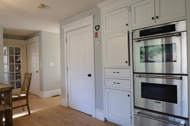 kitchen with white cabinetry, stainless steel double oven, and light wood-type flooring