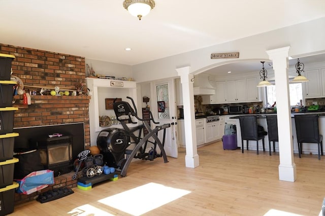 exercise area with light hardwood / wood-style flooring and ornate columns