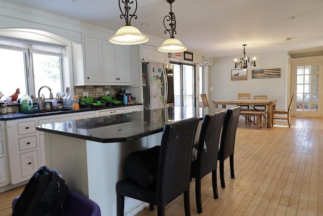 kitchen featuring white cabinetry, a kitchen island, pendant lighting, and stainless steel refrigerator