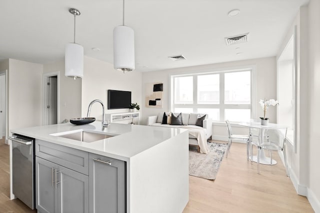 kitchen featuring sink, decorative light fixtures, light hardwood / wood-style flooring, dishwasher, and gray cabinets