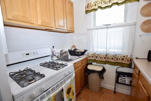 419-421 Court St, New Bedford, MA 02740 - kitchen with white range with gas cooktop, a sink, light countertops, light tile patterned floors, and decorative backsplash