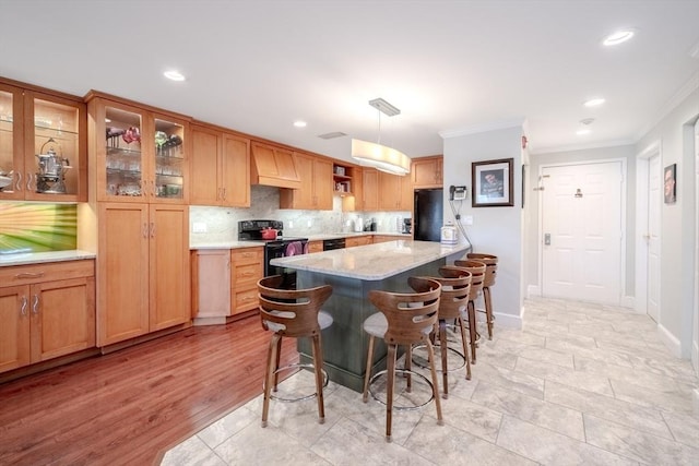 kitchen with pendant lighting, a breakfast bar area, backsplash, black appliances, and light stone countertops