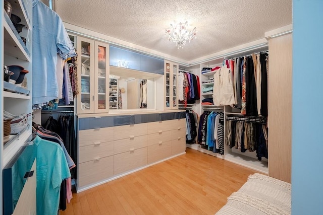 walk in closet featuring a notable chandelier and light hardwood / wood-style flooring