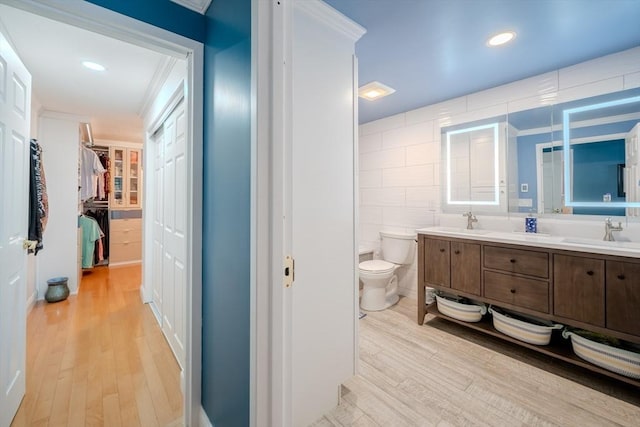 bathroom with toilet, tile walls, ornamental molding, vanity, and hardwood / wood-style floors