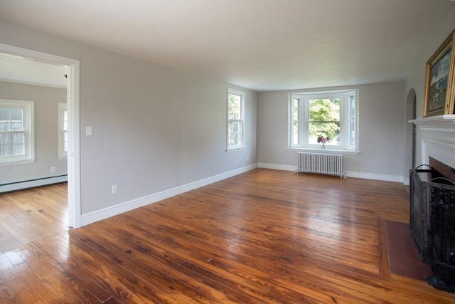 329 Read St, Somerset, MA 02726 - unfurnished living room featuring radiator, a fireplace with flush hearth, wood finished floors, and baseboard heating