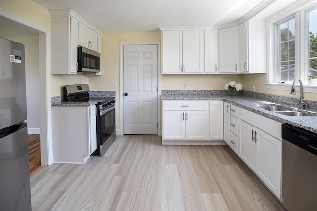 329 Read St, Somerset, MA 02726 - kitchen with appliances with stainless steel finishes, white cabinets, light wood finished floors, and light stone counters
