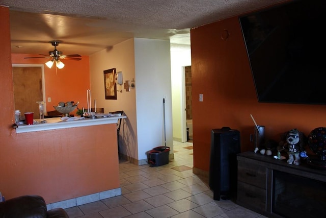 living area with a ceiling fan, light tile patterned flooring, and a textured ceiling