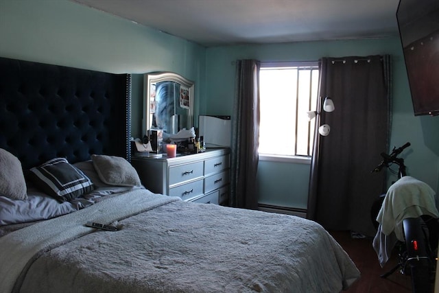 bedroom with a baseboard heating unit and dark wood-type flooring