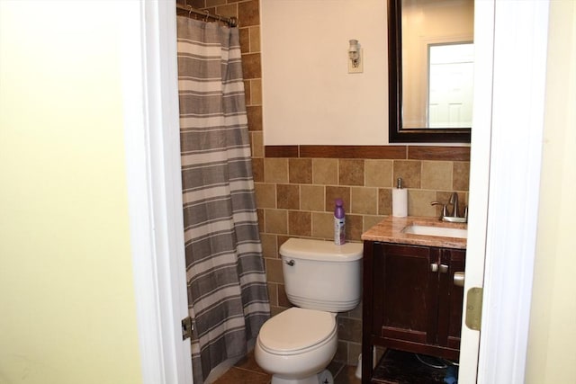 bathroom with toilet, curtained shower, vanity, and tile walls