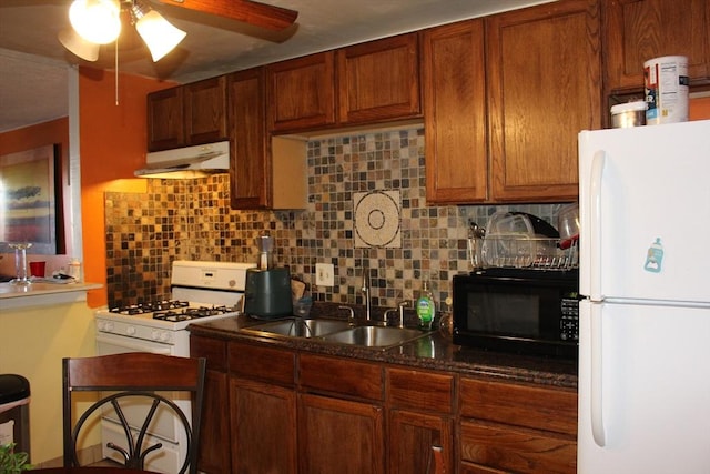 kitchen with tasteful backsplash, white appliances, a sink, and under cabinet range hood