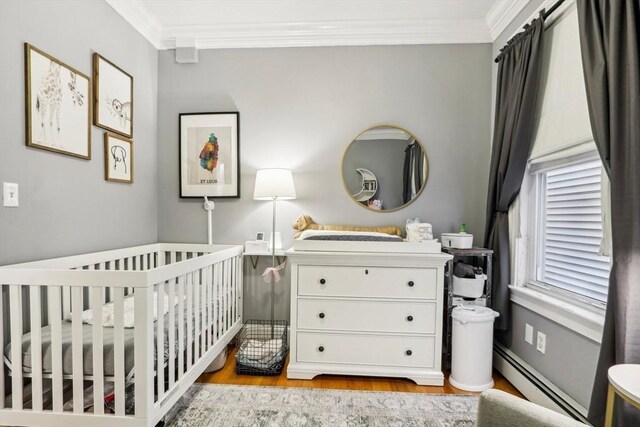 bedroom with a baseboard radiator, a nursery area, ornamental molding, and light hardwood / wood-style flooring