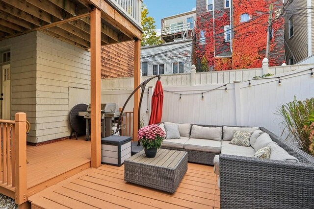 wooden terrace featuring area for grilling and an outdoor living space