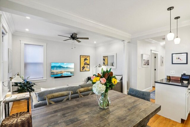 dining space with crown molding, decorative columns, ceiling fan, and light wood-type flooring