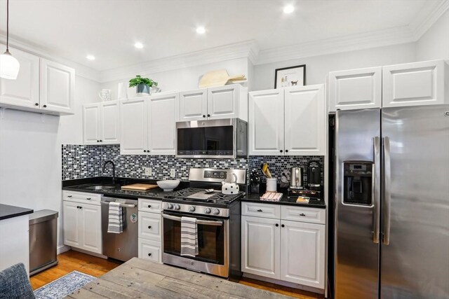 kitchen featuring white cabinetry, hanging light fixtures, sink, and appliances with stainless steel finishes