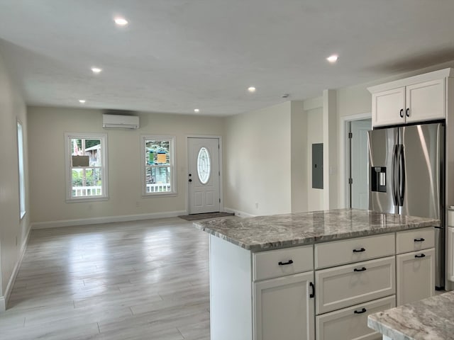 kitchen with light hardwood / wood-style floors, electric panel, white cabinetry, a wall mounted AC, and light stone countertops