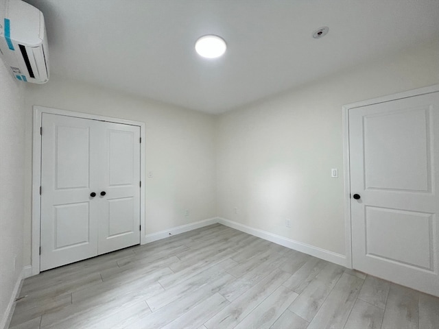 interior space with light wood-type flooring, an AC wall unit, and a closet