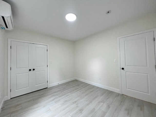 interior space with light wood-type flooring and a wall mounted air conditioner