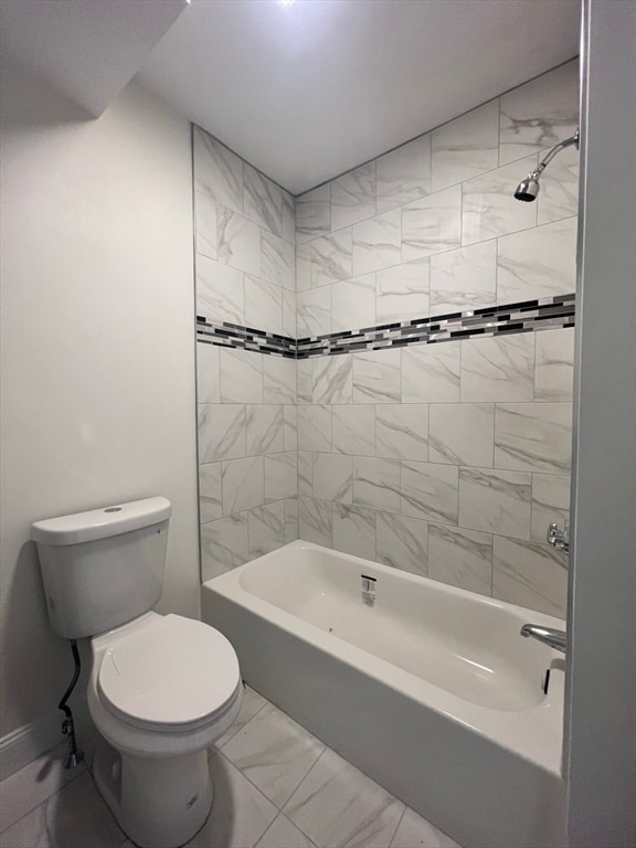 bathroom featuring toilet and tiled shower / bath